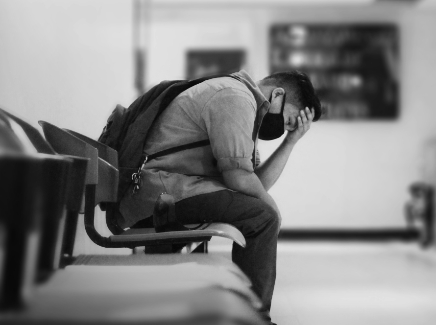 a man sits hunched over wearing a mask, representing suicidal thoughts