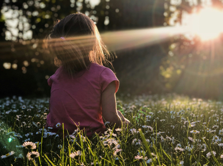 a little girl sitting in a sunny forest, represents calming the nervous system