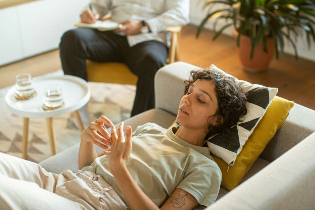 Woman laying on couch in room with natural light receives trauma-informed therapy.