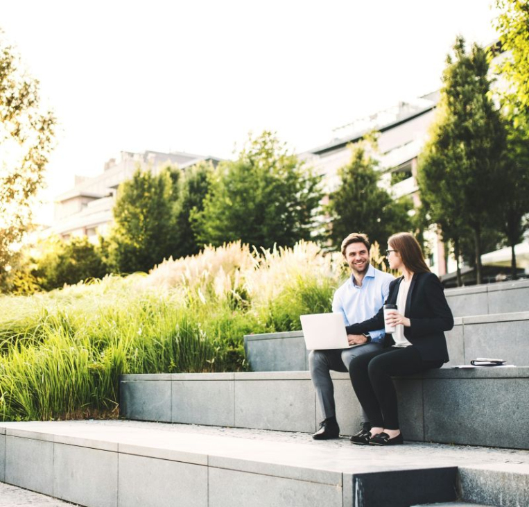 Two colleagues sit outside discussing work and offering each other support and respect as therapists.