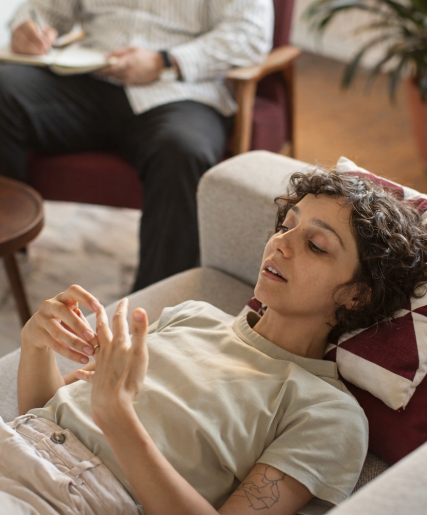 A woman lays on a couch next to a trauma-informed therapist and shares her experience and emotions in a safe and supported environment.
