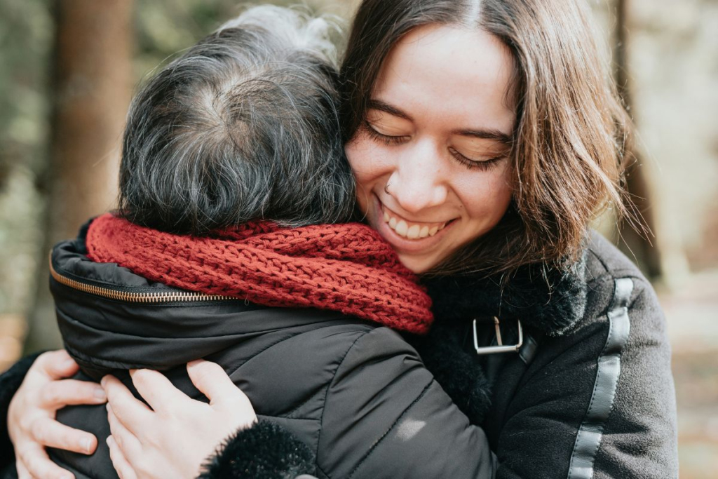 After receiving Relational Therapy at Brickel & Associates, a mother and adult daughter hug in a park.