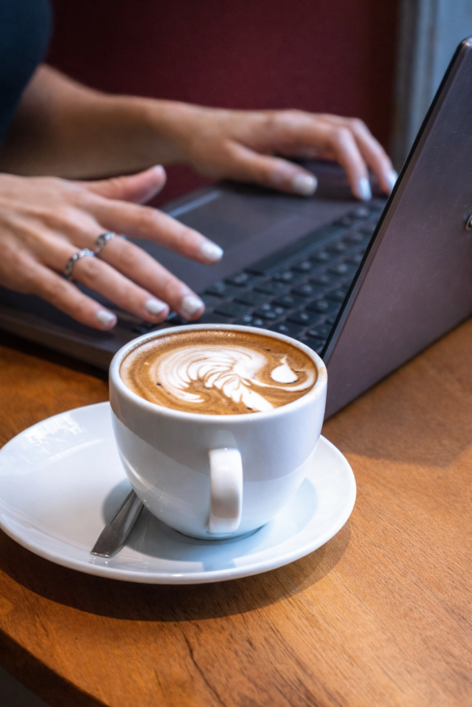 A women sits at her computer with a cup of coffee as she connects with Brickel & Associates by signing up for the wellness newsletter