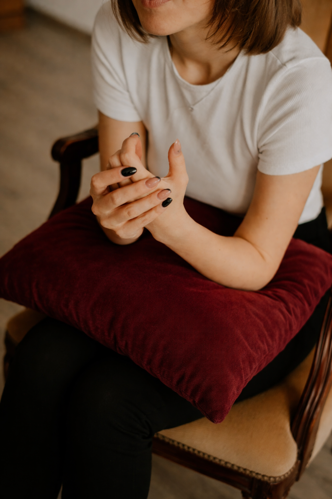 A woman sits in a therapy office chair looking hesitant but is supported through strengths-based therapy.